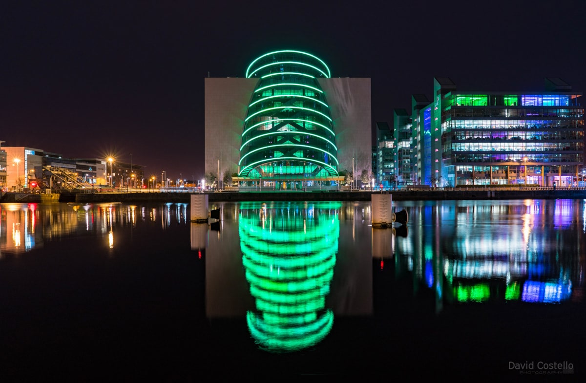 The Convention Centre illuminated in vibrant green for the Easter rising centenary reflecting in the placid river Liffey.