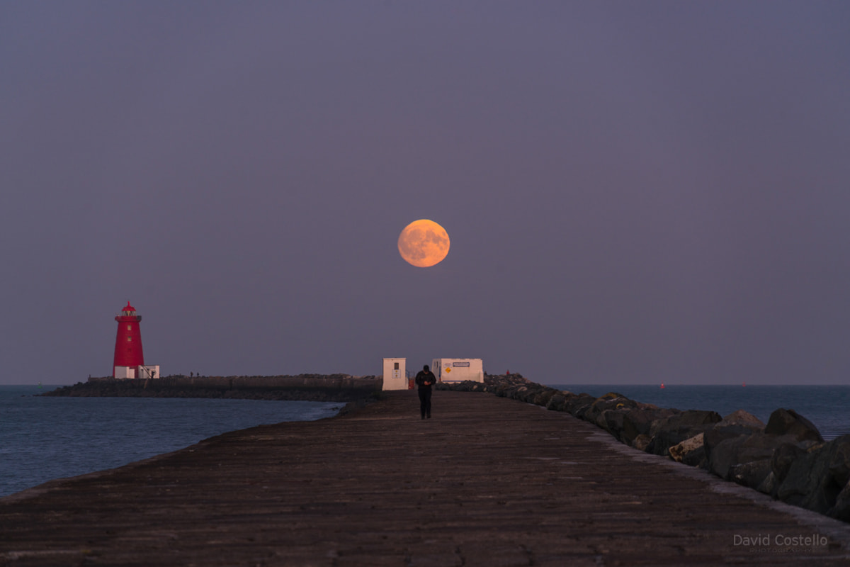 The full moon rising above the half moon swimming club on the Great South Wall in Dublin.