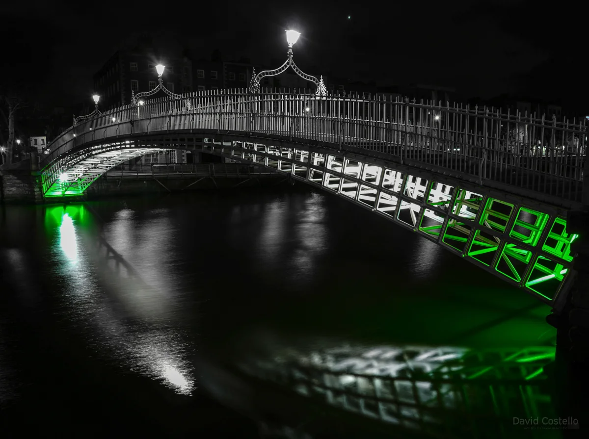 The Ha'penny Bridge lit in green for St.Patrick's Day reflecting in the river Liffey.