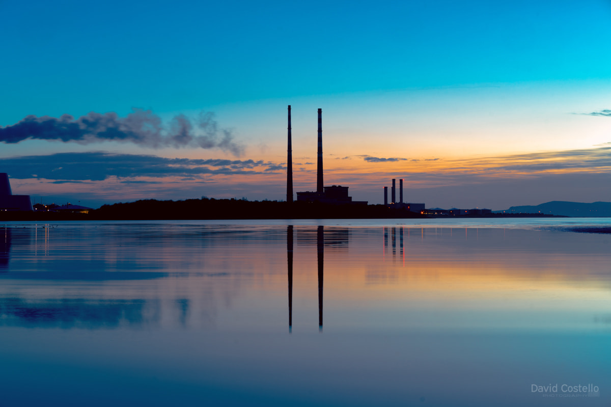 A dawn silhouette of the Dublin Towers reflecting on the peaceful waters of Sandymount Strand in spring.