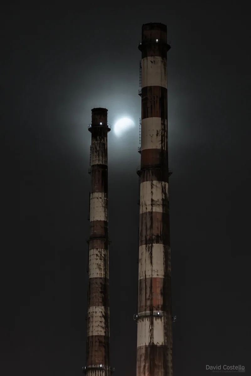 The super blood moon lunar eclipse breaks through the cloud and between the Chimneys on a misty Dublin night.