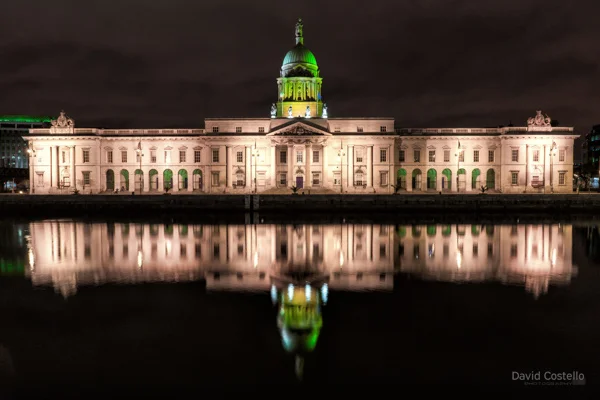 The Custom House with green lighting for St. Patrick's Day while reflecting in the river Liffey.