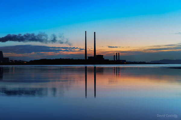 Dublin Towers silhouette at dawn with a colourful sky and reflecting in the sea at Sandymount Strand.