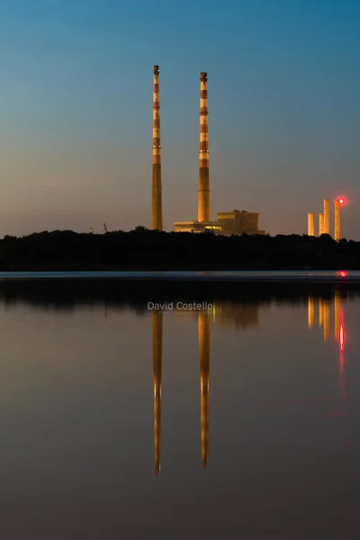 Poolbeg Chimneys colourfully reflecting in the water just after sunset on Sandymount Strand.