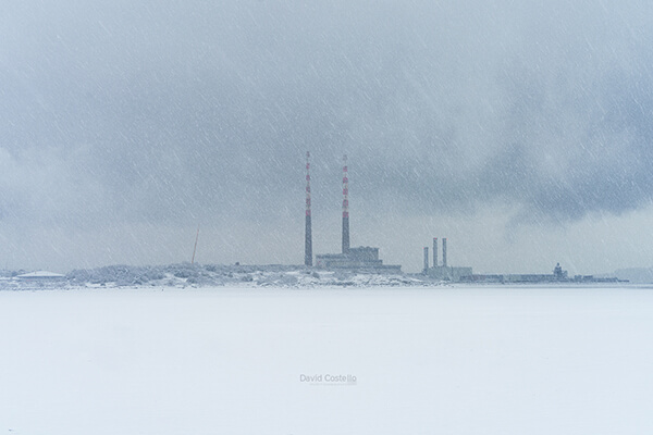 The iconic Poolbeg Chimneys photographed as the snow falls across Sandymount Strand and Dublin City.