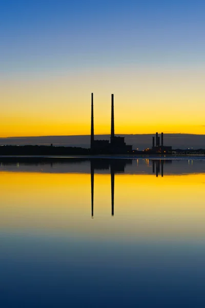 Symmetrical silhouettes from Sandymount Strand of the Poolbeg Chimneys at dawn.